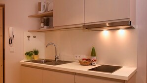 Een keuken met een dubbele spoelbak, een roestvrijstalen kraan en een inbouwafzuigkap. Op het aanrecht staan potplanten en er ligt een mand met fruit.