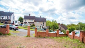 A residential street with houses, parked cars, and a delivery van.