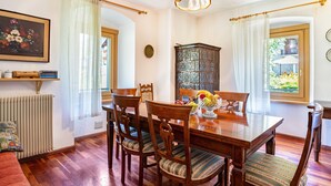 A dining room with a wooden table, chairs, a fruit bowl, and a cabinet.