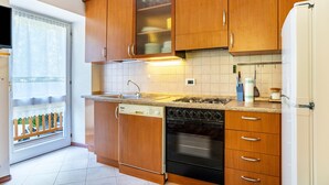 A kitchen with wooden cabinets, a dishwasher, an oven, and a refrigerator.