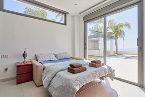 A bedroom with a bed, a nightstand, a lamp, and a view of the outside. - Villa 'Palacio Nazari' with Private Pool, Wi-Fi and Air Conditioning (Malaga)