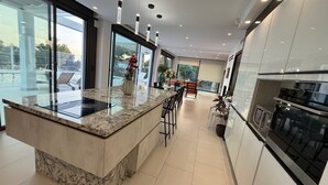 Una cocina moderna con encimera de mármol, electrodomésticos de acero inoxidable y vistas al exterior.