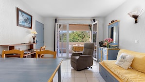 Una habitación con mesa de comedor, sillas, sofá, sillón reclinable, lámpara, espejo y vistas a través de un ventanal.