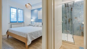 A bedroom with a bed, a bedside table, a lamp, and a window. - "Isabel Beach and Bike" Apartment with Private Garden and Wi-Fi (Finale Ligure)