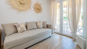 A modern living room with a beige sofa, decorative wall art, and a view of an outdoor patio. - "Isabel Beach and Bike" Apartment with Private Garden and Wi-Fi (Finale Ligure)