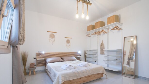 A bedroom with a wooden bed, bedside tables, a wardrobe, a mirror, and a hanging light fixture. - Apartment "Aurisa" with Private Terrace & Wi-Fi (Bari)