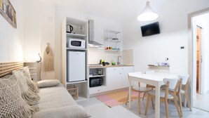 A compact living space with a kitchenette, a dining area, and a sofa with macrame pillows. - Apartment "Aurisa" with Private Terrace & Wi-Fi (Bari)