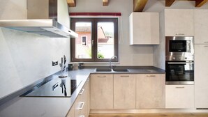 Eine moderne Küche mit Dunstabzugshaube aus Edelstahl, doppelter Spüle und eingebautem Backofen.