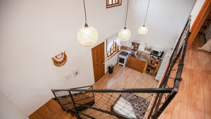 A staircase with a metal railing leading to a kitchen area with wooden flooring, a stove, and hanging pendant lights. - RSC02 Praia do Estaleito by ReservaStar (Balneário Camboriú)