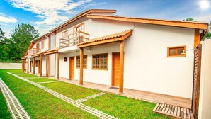 A two-story house with a balcony, a wooden porch, and a well-maintained lawn. - RSC02 Praia do Estaleito by ReservaStar (Balneário Camboriú)