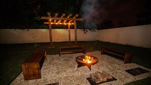 An outdoor patio area with a fire pit, wooden benches, and a pergola with string lights. - RSC02 Praia do Estaleito by ReservaStar (Balneário Camboriú)