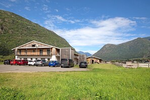 En bygning med flere etager, en parkeringsplads med flere biler og et bjergrigt baggrundsmiljø.