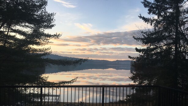 A deck with a view of a lake and mountains.