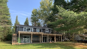 A two-story house with a covered patio and a large lawn.