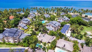 A coastal residential area with multiple houses, some with solar panels, surrounded by palm trees and a beach. - Walk to the beach & restaurants @ Las Terrenas for 10! (Las Terrenas)