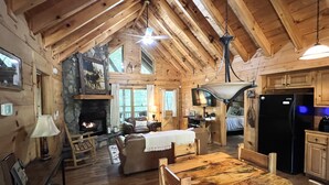 Interno di una baita in legno con camino, mobili in legno e angolo cottura.