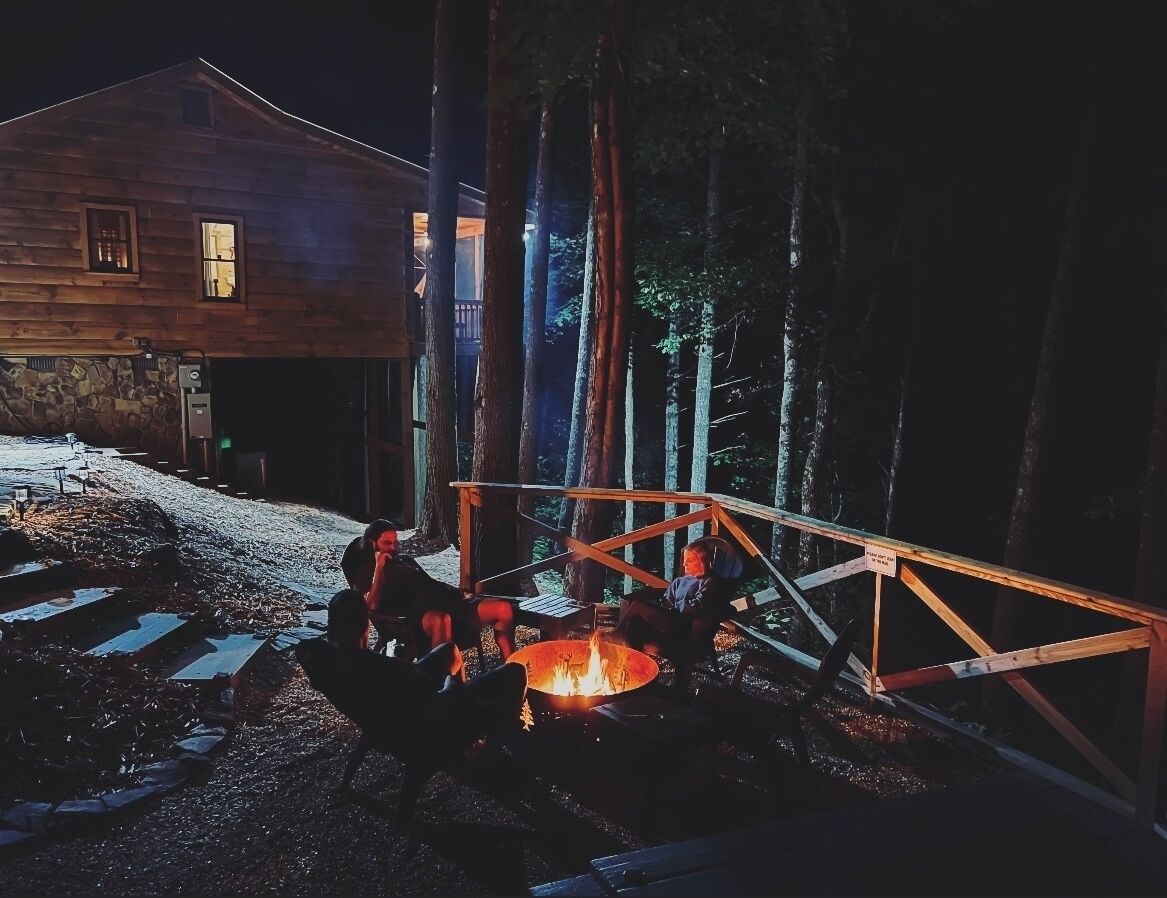 A rustic cabin with a fire pit and a wooden deck.