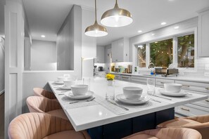 Una cocina moderna con una isla central, iluminación colgante y vistas al exterior.