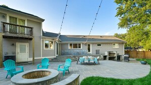 A backyard with a stone fire pit, outdoor seating, and a barbecue grill. - 6 Bed High End Home w/ EPIC Backyard! (Arlington)