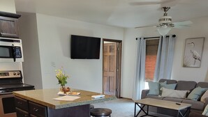 A modern kitchen with a built-in microwave, a dining area with a marble table, and a living room with a sofa and a ceiling fan. - Century Cafe Flat (Kewaskum)