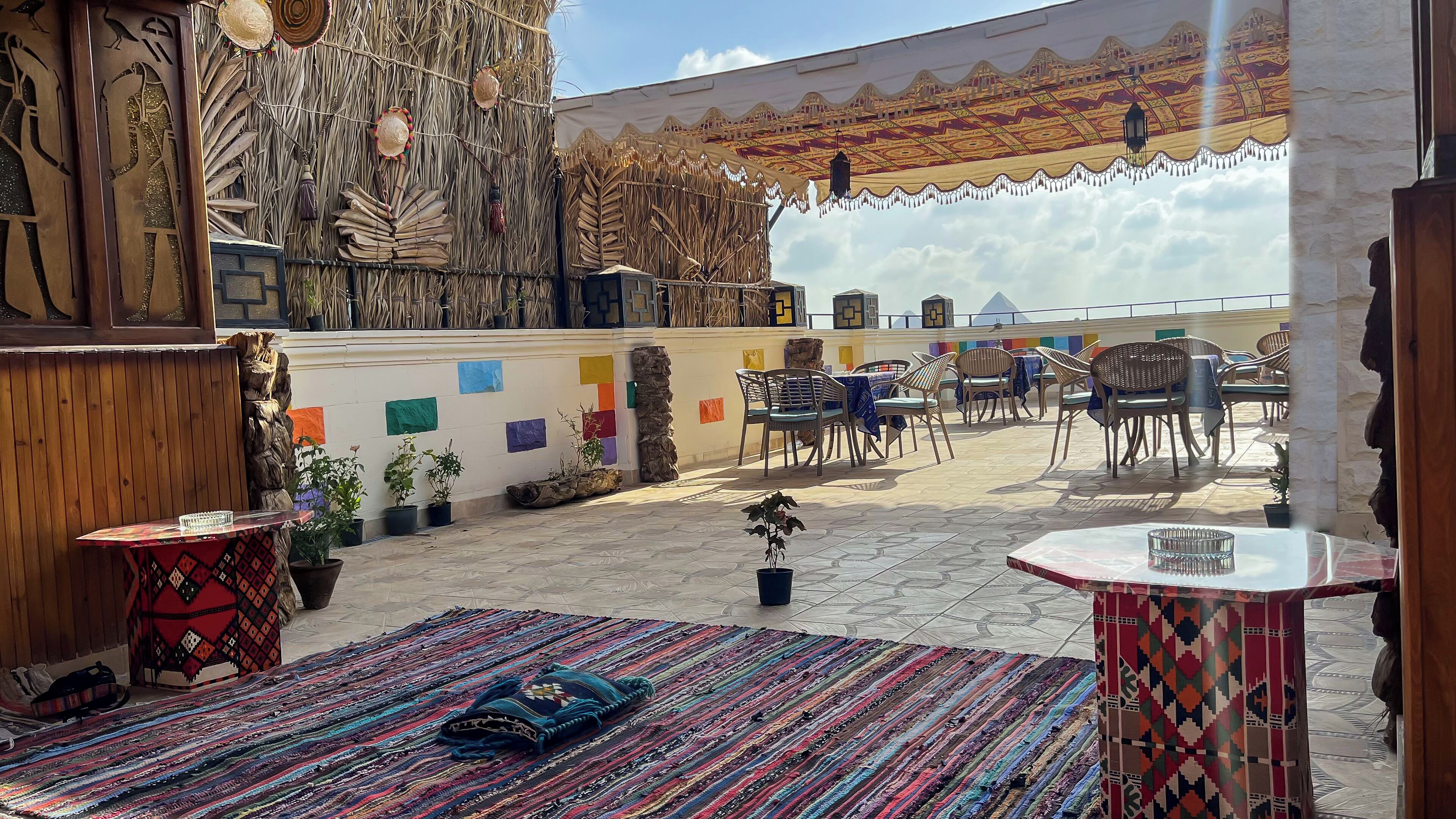 Terraza en la azotea con un muro decorado, mobiliario exterior y plantas en macetas.