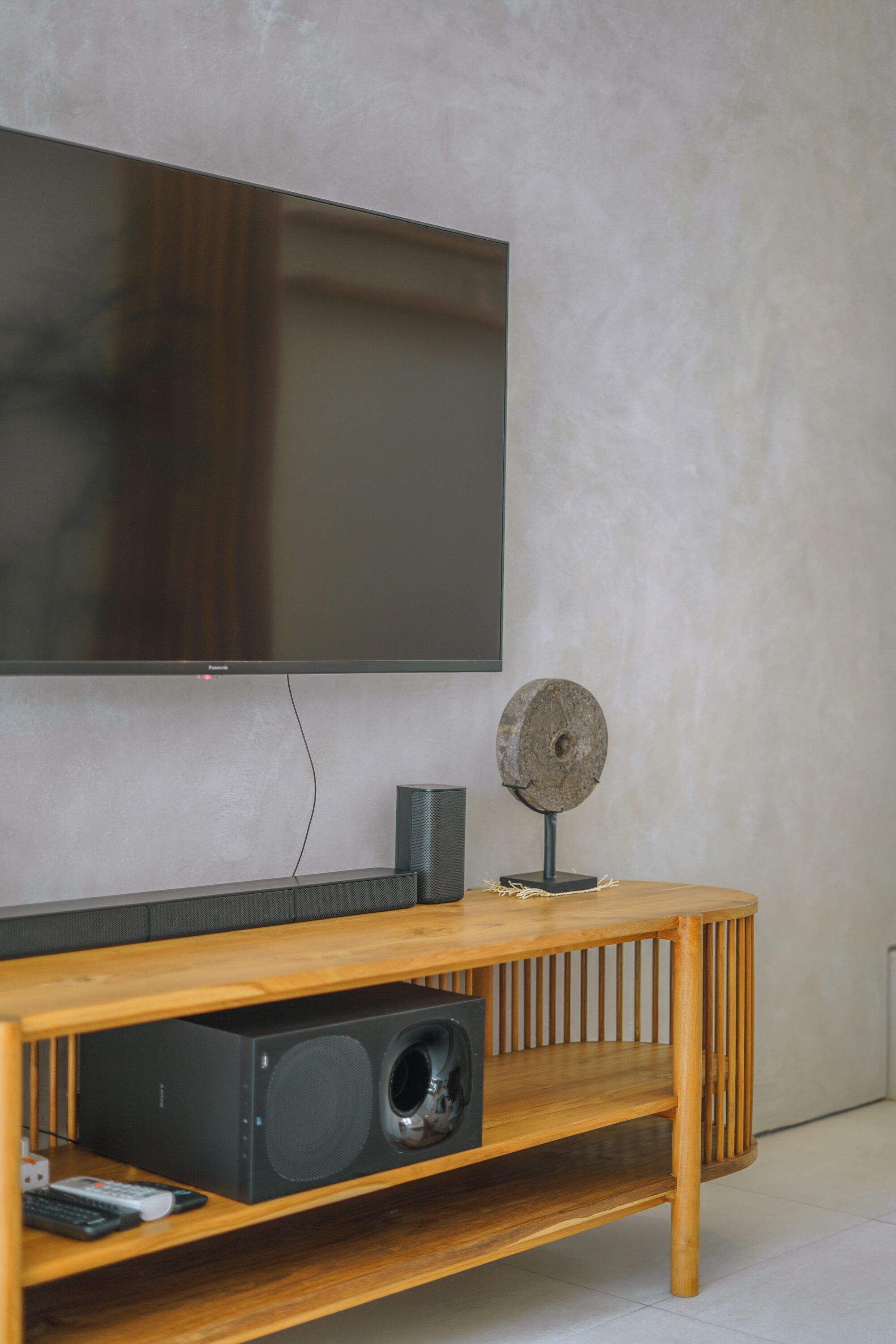 Ein Holzerhaltungsschrank mit einem flachbildfernseher an der Wand, einem Lautsprecher und einem Dekorationsgegenstand darauf.