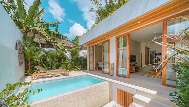 A modern house with a swimming pool, wooden deck, and large glass doors leading to a living area. - Villa Cocoon - Gaia (Canggu)
