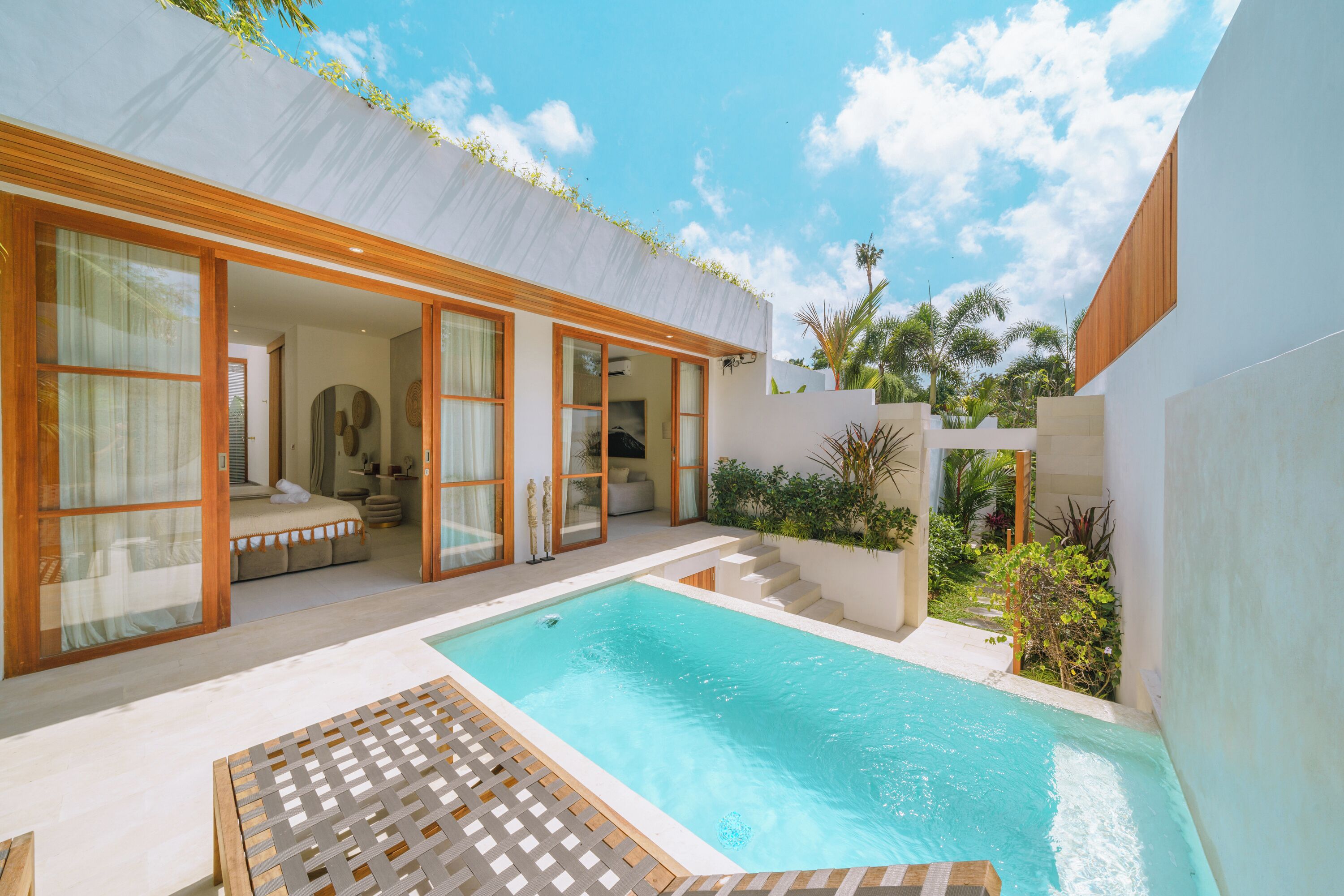A modern house with a swimming pool, large glass doors, and a patio area.
