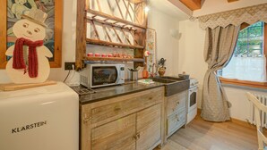Een keuken met houten kastjes, een magnetron en een koelkast.
