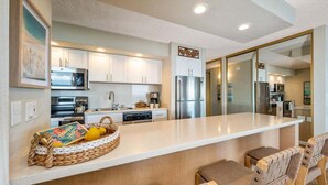 Una cocina moderna con armarios blancos, electrodomésticos de acero inoxidable y una isla central con asientos.