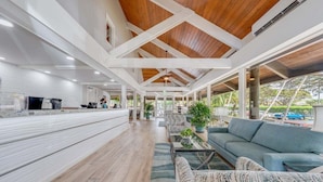 Un amplio espacio interior con techos altos, vigas de madera y una variedad de zonas de estar, incluyendo sofás y sillones.
