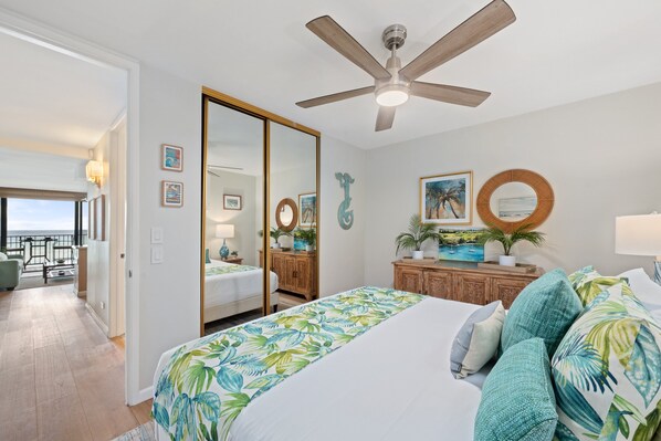Une chambre d’hôtel avec un lit, un ventilateur de plafond, une vue sur l’océan et un balcon équipé de mobilier d’extérieur.