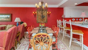 Un coin repas avec un mur rouge, un lustre et une table dressée pour six personnes.