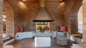 A cozy room with a brick fireplace, a white bench, and a wicker basket.