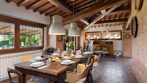 A dining area with a long wooden table set for a meal, surrounded by chairs.