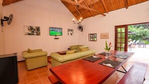 A cozy living area with a wooden ceiling, a TV, and artwork on the walls. - 2 bed Apartment With Pool - 2126 (Victoria Falls)