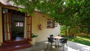A patio with a table and chairs, a fire extinguisher, and a potted plant. - 2 bed Apartment With Pool - 2126 (Victoria Falls)
