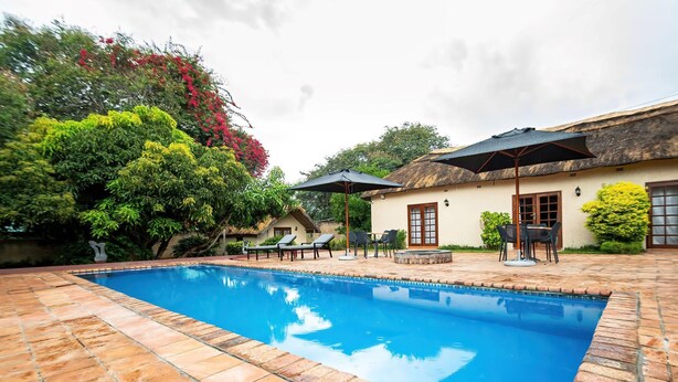 A swimming pool with tiled edges, lounge chairs, and umbrellas. - 2 bed Apartment With Pool - 2126 (Victoria Falls)