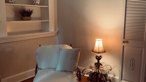A bedroom with a bed, a bedside lamp, a door, and a shelf with decorative items. - The Indigo House- Located in the heart of Historic Hannibal, Missouri  (Hannibal)