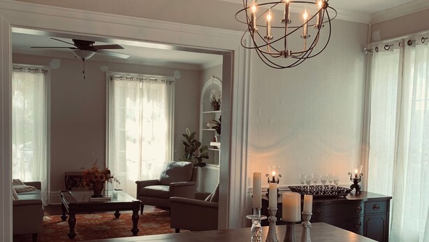 A spacious dining area with a dark wooden table, a chandelier, and a view into the adjacent living room. - The Indigo House- Located in the heart of Historic Hannibal, Missouri  (Hannibal)