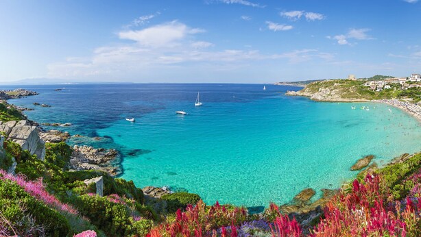 A coastal view with clear turquoise waters, rocky coastline, and a beach with umbrellas. - Relaxing Cristal Bedroom Apartment Sleeps Num1502 (Santa Teresa di Gallura)