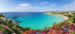 A coastal view with clear turquoise waters, rocky coastline, and a beach with umbrellas. - Relaxing Cristal Bedroom Apartment Sleeps Num1502 (Santa Teresa di Gallura)