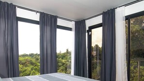 Een slaapkamer met een bed, grote ramen en een balkon.