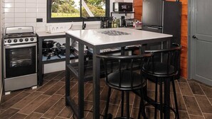 Een moderne keuken met een centraal kookeiland, barstoelen, een kookplaat, magnetron en koelkast.