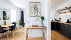 A modern kitchen with wooden cabinets, a countertop, and a dining area with a table and chairs. - Barney's Beach House - A Haven of Comfort and Style (Narrawallee)
