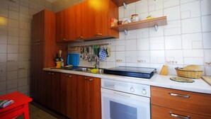 A kitchen with wooden cabinets, a built-in oven, and a countertop with various kitchen items. - Gorgeous Beach House (Alcamo)