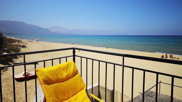 A balcony with a yellow cushion, overlooking a beach with clear blue water and distant mountains. - Gorgeous Beach House (Alcamo)