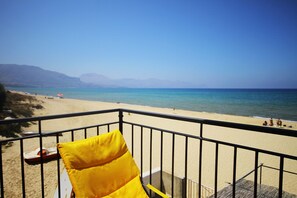 A balcony with a yellow cushion, overlooking a beach with clear blue water and distant mountains. - Gorgeous Beach House (Alcamo)