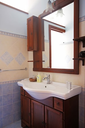 Un bagno con un lavandino bianco, mobili in legno, uno specchio e un portascope.