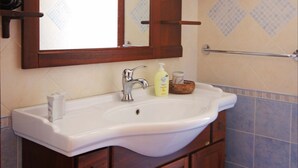 A bathroom with a white sink, wooden cabinets, a mirror, and a towel rack. - Gorgeous Beach House (Alcamo)